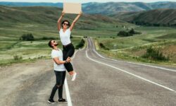 A young couple is voting on the road. A happy couple hitchhiking and voting with a sign on the road