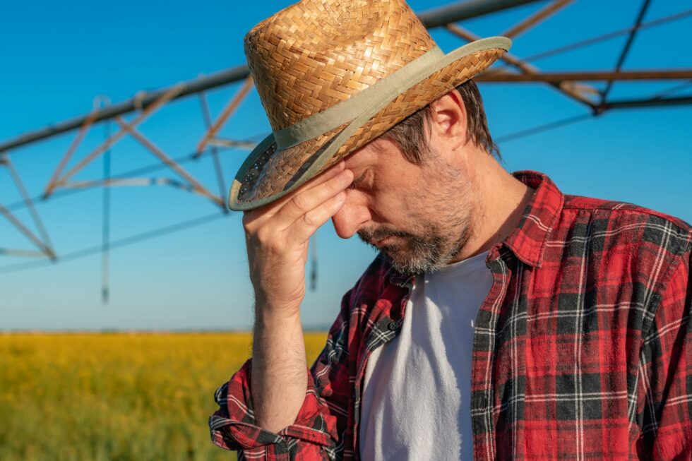 Portrait of serious farmer standing in front of center-pivot irrigation equipment in rapeseed field