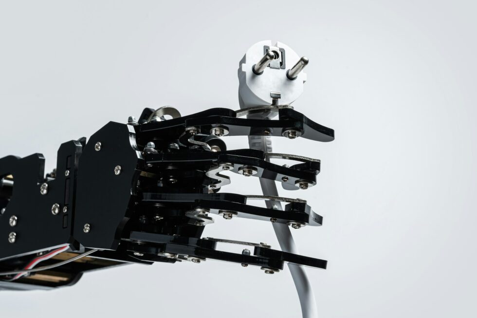 Real robotic hand with power plug. Concepts of AI takeover and Technological singularity